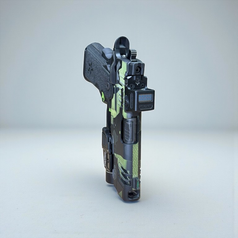 Green patterned pistol photographed from the front