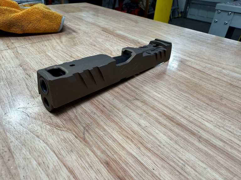 Machined pistol slide on a workshop bench
